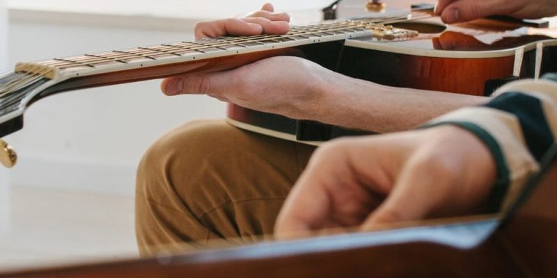 Teacher giving guitar lessons to pupil in a classroom